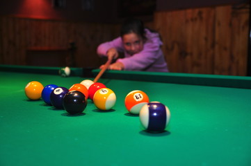 girl with a cue in hands plays billiards