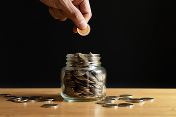 Businessman is putting a coin in a glass bottle. Money stack for business planning investment....