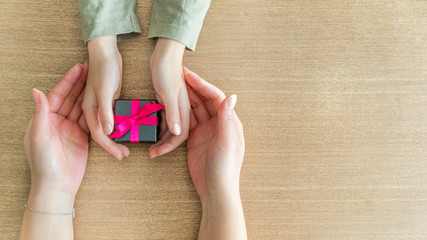 Mains s'offrant un cadeau sur une table en bois
