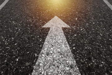 Asphalt road with an arrow pointing forward on the surface. An image of a milestone roadmap is a...