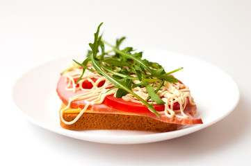 Sandwich of bread for toast, sturgeon, tomatoes, arugula, cheese and mayonnaise on a white background in a plate