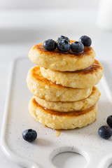 Cottage cheese pancakes with fresh blueberries and honey. Russian syrniki or sirniki, cottage cheese fritters or pancakes served with berries. Restaurant menu, cookbook recipe