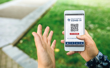Mobile phone with not immune digital health passport for covid-19 held by an unrecognizable woman