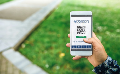 Mobile phone with immune digital health passport for covid-19 held by an unrecognizable woman