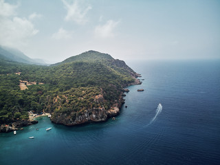 Naklejka premium turkey, aerial drone perspective of deep blue and turquoise water of the mediterranean sea. Moody weather with many green trees. nice sandy white yellow beach