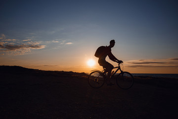 Fototapeta premium Silhouette of cyclist in motion at beautiful sunset.