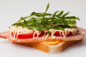 Sandwich made of bread for toast, balyk, tomatoes, arugula, cheese and mayonnaise on white plate side view