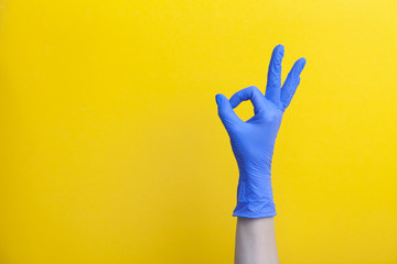 Doctor hand in medical lilac surgical rubber glove shows gesture okay