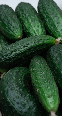 Lots of green cucumbers, spring vegetables, vegetables on the table, cucumbers in a basket on a white table