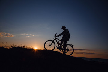 Fototapeta na wymiar silhouette of a hipster man on a bicycle on sunset background