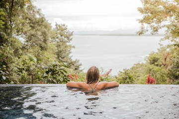 young woman relaxes in the pool at home during a relaxing bath looking calmly at the sea