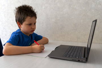 A young boy is learning remotely on a laptop at a desk