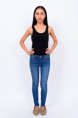 Full body shot of young beautiful Asian woman thinking