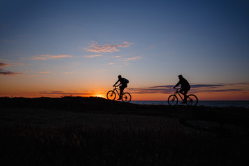 Obraz na płótnie Canvas two friends on bikes enjoy a beautiful sunset