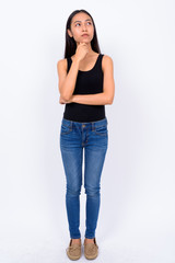 Full body shot of young beautiful Asian woman thinking