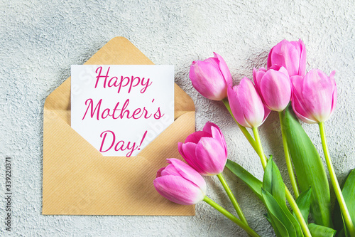 Mother's day Holiday Concept. Pink tulips flowers and card on concrete background. Greeting card for Womens or Mothers Day. Flat lay, top view.