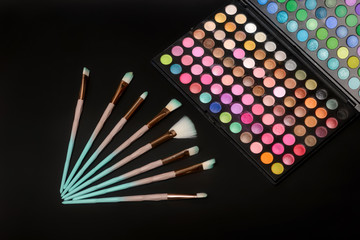 Color palette of eye shadows and brushes for professional make-up artist on a black background