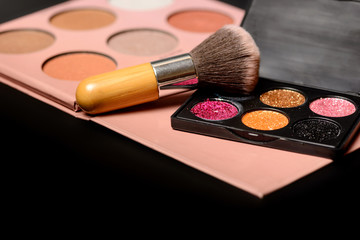 Color palette of eye shadows and brushes for professional make-up artist on a black background