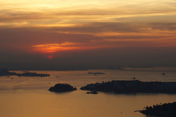 Fototapeta na wymiar Sunset at Niteroi and Rio de Janeiro cities, Brazil. View of tourist spots in the cities, such as Guanabara Bay, Sugarloaf Cable Car, Christ the Redeemer statue