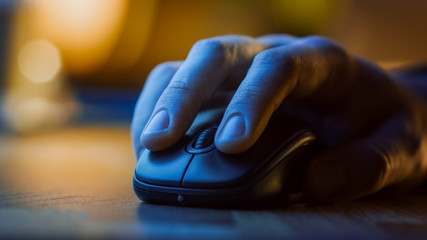 Close-up Macro Shot: Person's Hand Using Wireless Computer Mouse, Scrolls through Apps and Websites with a Wheel and Clicks on Buttons. In the Background Evening Light