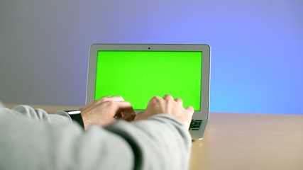 Man's hands are typing on a keyboard on a laptop with a green screen. Stay home to work with a laptop on the screen of which chromakey. Coronavirus or covid-19