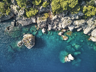 Fototapeta premium Sharp stones and rocks in the turquoise, blue sea. Drone aerial shot from above with white stone coast. Turkey