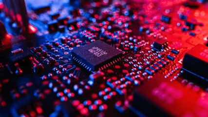 Close-up Macro Shot of Microchip, CPU Processor, Printed Circuit Board or Computer Motherboard with Components: Inside of Electronic Device. Neon Colors. Cyber Security Safety Concept.