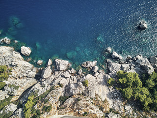 Obraz premium Sharp stones and rocks in the turquoise, blue sea. Drone aerial shot from above with white stone coast. Turkey