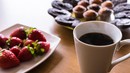 candy dessert with cupckaes, handmade butterfly cookies, dish with strawberries and cup of coffee