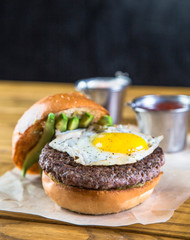 Opened burger with egg and avocado on wooden table