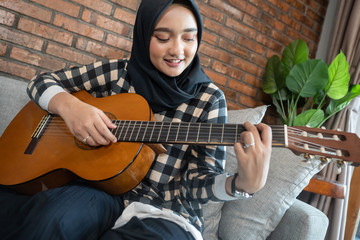 beautiful muslim woman play guitar while staying home