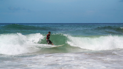 Fototapeta na wymiar Homem surfando isolado no meio da onda em dia ensolarado.