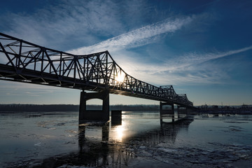Fototapeta na wymiar Bridge over Icy river at dawn with cloudscape