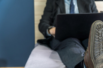 Home office concep with a man dressed in a suit in bed with a laptop