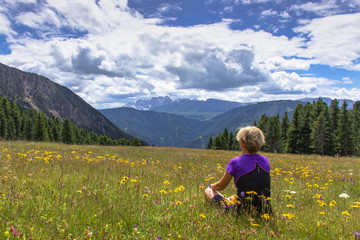 Incredible nature landscape in Dolomites Alps. Spring green blooming meadow. Panorama of mountains. Happy woman hiking in mountains.Active lifestyle.Girl backpacker,adventure vacations.Summer holiday
