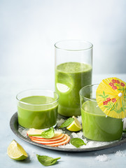 Spinach apple smoothie in a glasses on a light background with copy space. Drink, healthy dieting and nutrition, lifestyle, vegan, alkaline, vegetarian concept.