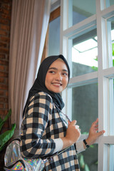 atractive muslim woman at home standing next to the window in the morning