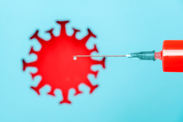 Syringe with vaccine drug and abstract red coronavirus, virus, bacteria, microbe on blue background. Concept vaccination and infectious diseases, pandemic Covid -19