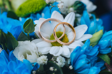Wedding gold rings close-up on multi-colored flowers: chrysanthemums, asters, eustomas. Photography, concept, macro.