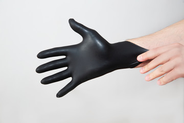 Someone puts on their hands black protective gloves to protect against germs and bacteria to protect against infection