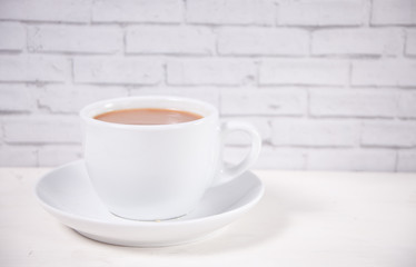 Porcelain cup of tea with milk on the white table.