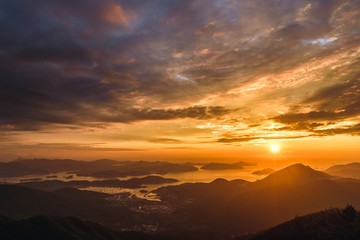 Beautiful aerial shot of a sea surrounded by hills under a cloudy sky at sunset