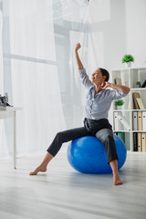 beautiful happy businesswoman stretching on fitness balls in office