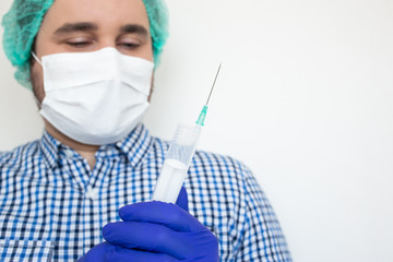 Doctor in mask holds an injection syringe and vaccine isolated on white background. Vaccine from, flu, coronavirus, ebola. Epidemic of the coronavirus.