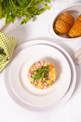 Russian traditional salad Olivier with vegetables and meat in the white plate.