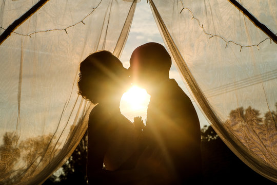 A romantic kiss of the bride and groom against the sunset. Their love will last forever. 