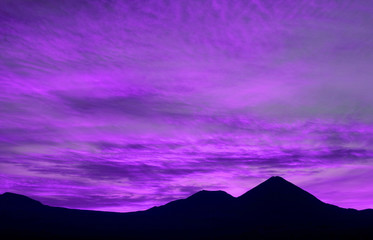 Pop art style vibrant purple colored twilight sky over the mountains silhouette 