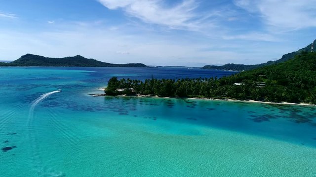 Nice drone shot of speedboat boating through the turquoise tropical lagoon turquoise blue water of Bora Bora, French Polynesia a vacation tourism paradise holiday