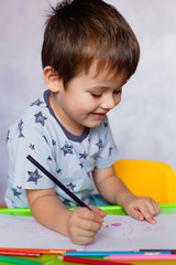 Little boy drawing with color pencils. Boy, drawing a picture for fathers day. Small boy draws at the table.