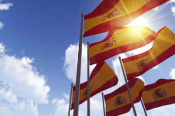 Spain flags waving in the wind against a blue sky. 3D Rendering